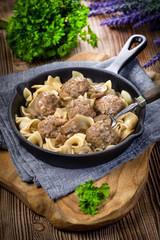 Pork meatballs with noodles in a cast iron skillet.