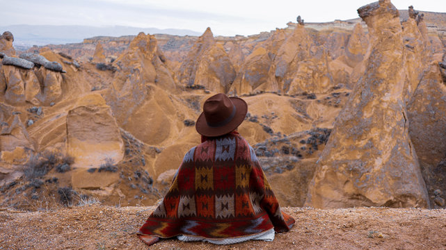 Woman alone with the volcanic landscape at Devrent Valley in Cappadocia. Girl walking around Fairy chimneys surronded by tufa formations at Imaginary Valley in winter season in Cappadocia, Turkey.