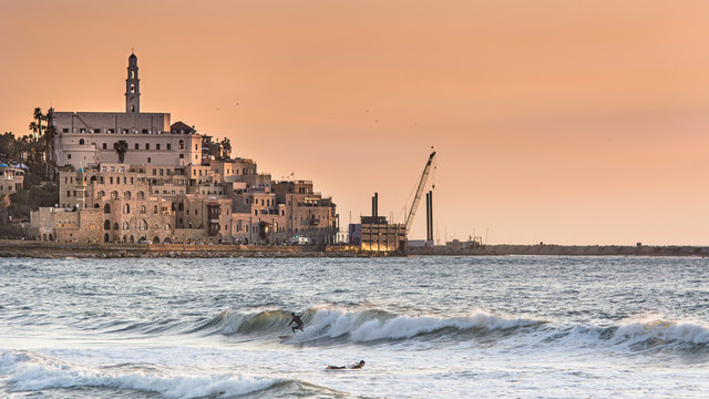 Saint Peter's Church Tel Aviv Israel, Port yafo, Old Jaffa,  Medieval twice destroyed and rebuilt, has a clock in the tower,and two people surfing at sunset