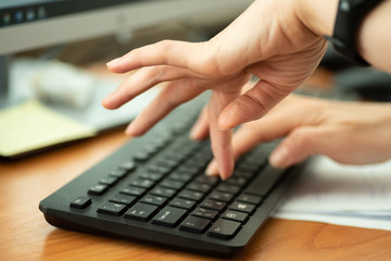 Woman typing text on keyboard, close up