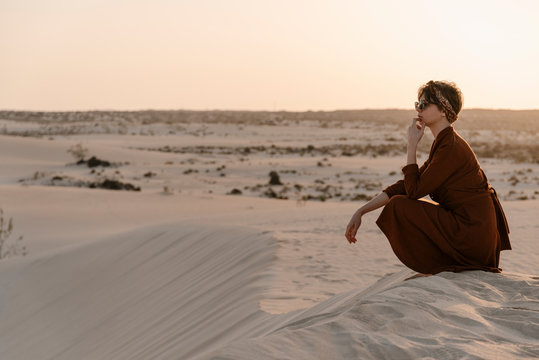 Brunette woman sitting at loneliness at desert.