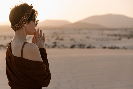 Brunette woman praying at loneliness at desert.