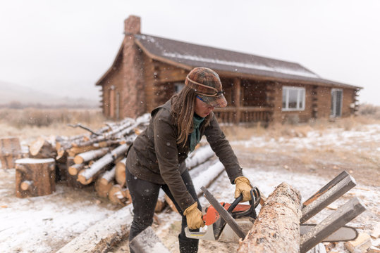Ranch Manager and Cowgirl  cutting wood with a chainsaw