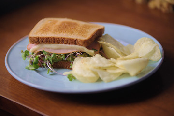 FOOD: a sandwich of toasted wheat bread with smoked turkey, cheese and bean sprouts; served with potato chips.
