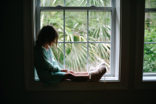girl sitting in window with palm trees
