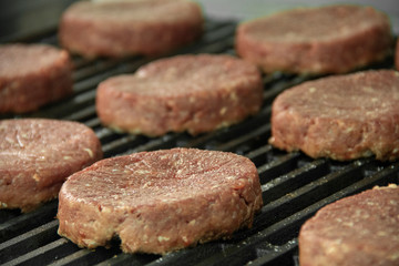 Raw hamburger patties sitting on hot char broiler grill