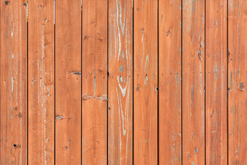 Photo of a fence made of wooden vertical boards. Brightly brown background, for layouts and sites.