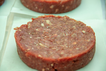 Close up of a raw hamburger patty sitting on paper