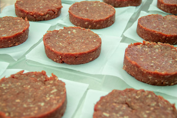 Many hamburger patties organized on top of white papers