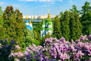 Panorama of the city of Kyiv, Ukraine. View of Vydubychi Monastery in spring with  lilac blossoming. View from botanical garden. Orthodox church. Landscape