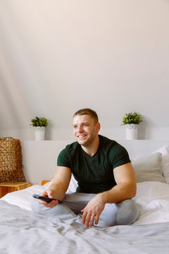 Cheerful man watching TV in bedroom