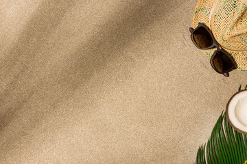 Fototapeta na wymiar Hat and sunglasses on sand background. Harsh light with shadows.