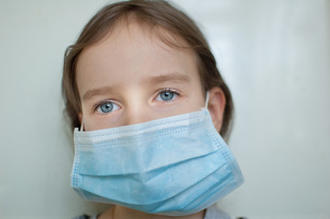 Coronavirus Covid-19 outbreak. Little blonde girl with blue eyes wearing disposable mask for protection of virus on white background in studio. Quarantine concept