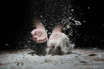 hands in flour on a black background. flour flies