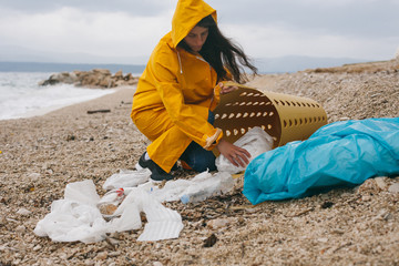 Woman cleaning up a beach from plastic