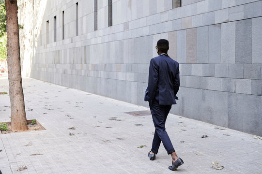 Faceless stylish black afro businessman walk to work.