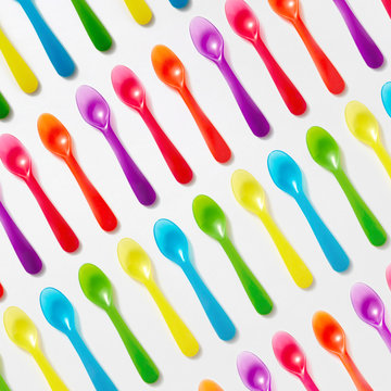Pattern of multi-colored plastic spoons on a light background. F