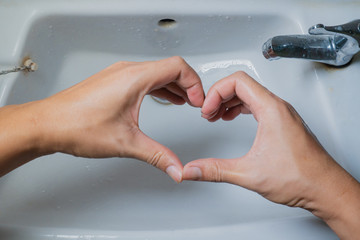 Heart-shaped hand in the bathroom sink