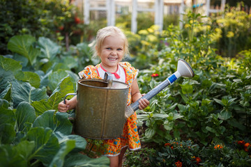 girl child in the garden watering plants, a small gardener, summer in the village