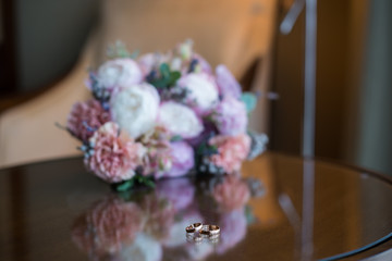 beautiful bridal bouquet of the bride, made of pink peonies and powdery-colored carnations, on a shiny table, against the background of an armchair, in an expensive hotel interior