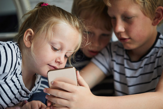 Three children using a smart phone together