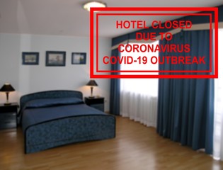 Defocused interior of a hotel room with a notice saying ''Hotel closed due to coronavirus COVID-19 outbreak''