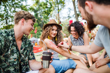 Group of young friends sitting on ground at summer festival.