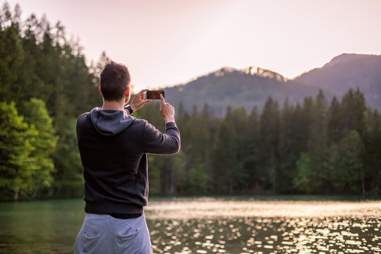 Young Man Taking Photos Of Landscape With Mobile Smart Phone