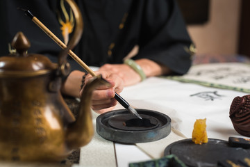 a man is engaged in Chinese calligraphy sitting at a table