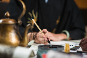  a man is engaged in Chinese calligraphy sitting at a table