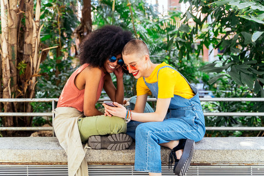 Beautiful lesbian couple using a mobile in the Street