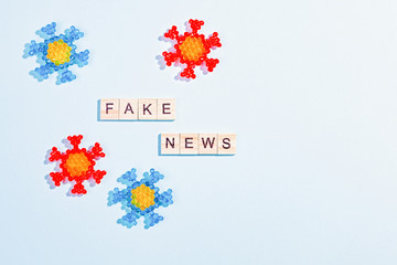 Words fake news made of wooden blocks with coronavirus model on blue background, flat lay, top view. Fake news about pandemic concept, disinformation in social media theme