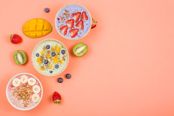 Fototapeta na wymiar Beautiful multi-colored healthy smoothie bowls with berries and superfoods on a bright background. Summer food for detox concept. Top view, flat lay, copy space.