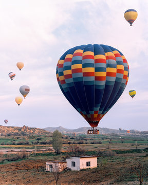 Hot air Balloons fly through a beautiful landscape in the mountains at sunrise