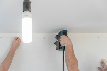 Repairman with hammer to make the hole in the wall for future installation of fastening of a tension ceiling