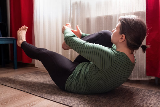 Sporty woman lying and doing stretching exercise at living room at home