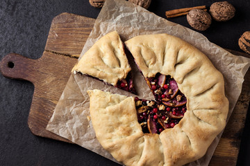 Homemade galette pie with apples, elder berries and walnuts decorated with fresh cowberry