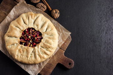 Homemade galette pie with apples, elder berries and walnuts decorated with fresh cowberry