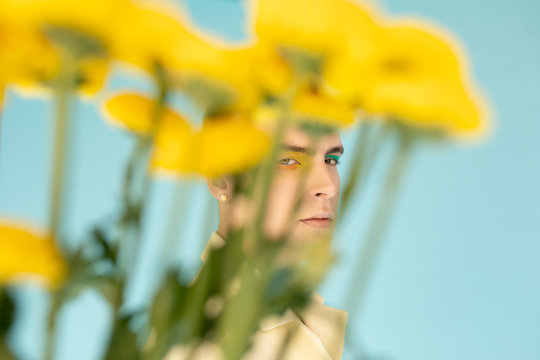Male model looking at camera from behind flowers