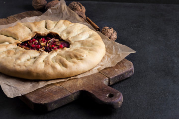 Homemade galette pie with apples, elder berries and walnuts decorated with fresh cowberry