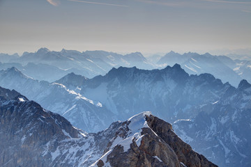 Elevated view of snowy Jubilaumsgrat ridge with jagged Dreitorspitze peak in morning haze layers, Wetterstein and Karwendel mountains, Bayerische Alpen Northern Limestone Alps Bayern Germany Europe