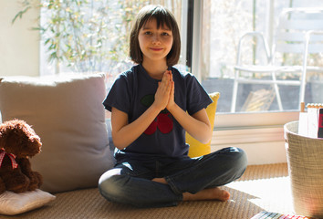 smiling child in lockdown enjoying namaste while practicing relaxing yoga