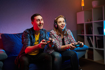 Portrait of crazy playful couple, Gamers enjoying Playing Video Games on Playstation indoors...