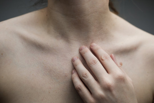 Woman with no face touching her hand to her neck and exposing her collar bones and d&eacute;colletage; pale skin, freckles and moles