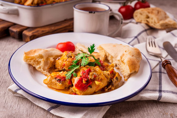 Chicken stew with vegetables on a white plate with a blue border. Dining table setting. Georgian cuisine - chakhokhbili.