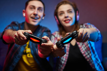 Portrait of crazy playful couple, Gamers enjoying Playing Video Games on Playstation indoors sitting on the sofa, holding Console Gamepad in hands, Xbox fans. Resting At Home, have a great Weekend