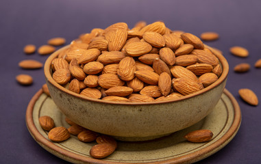 Pile of roasted almonds in a wooden pot close up view