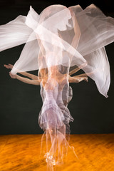 Multiple exposure of ballerina in purple, dancing with white fabric.