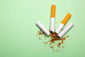 Two broken cigarettes on a green background
