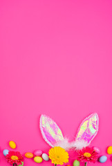 Obraz na płótnie Canvas A lot of colored easter eggs, on a pink background. Bunny ears as a symbol of the spring holiday. Happy Easter card with copy space for text. Minimal style.